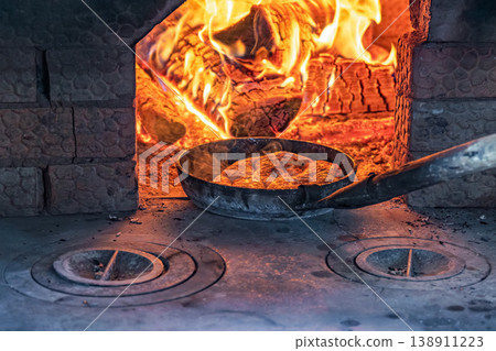 Baking bread in a rustic brick oven with firewood and glowing flames 138911223