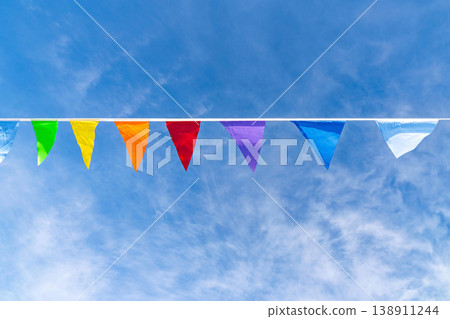 Colorful triangular pennant flags hanging on a line against bright blue sky 138911244