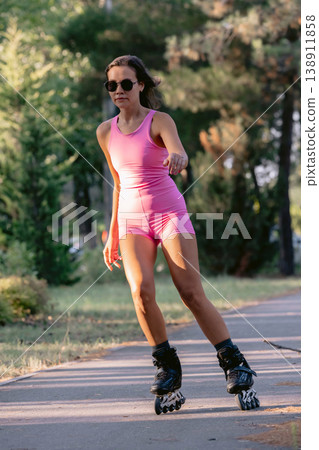 Woman roller skating in park wearing pink outfit Woman roller skating in park wearing pink outfit 138911858