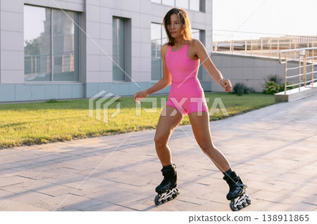 Young woman roller skating outdoor in pink outfit Young woman roller skating outdoor in pink outfit 138911865