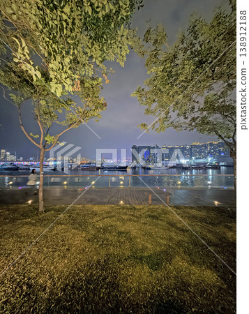 Nighttime harbor view with boats and city skyline illuminated by vibrant lights Nighttime harbor view with boats and city skyline illuminated by vibrant lights 138912188