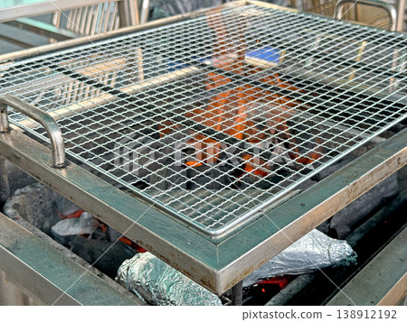Close up of a hot grill grate over glowing embers and charcoal briquettes Close up of a hot grill grate over glowing embers and charcoal briquettes 138912192