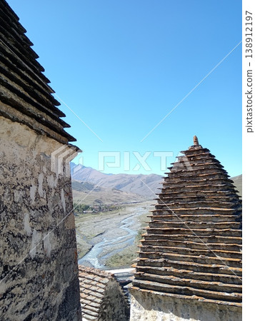 View of the City of the Dead, Dargavs, North Ossetia, Russia. Row of white tombs against the backdrop of the Caucasus Mountains 138912197