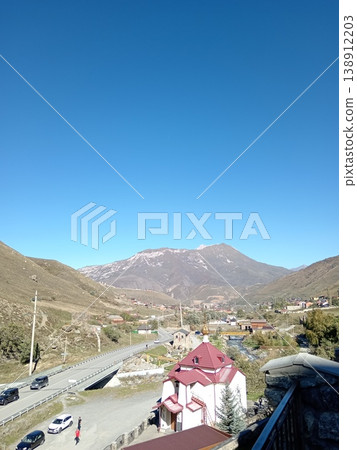 Hidikus mountain village, Kurtatinsky Gorge, North Ossetia, Russia, bright summer day. Small community of stone houses surrounded by Caucasus peaks Hidikus mountain village, Kurtatinsky Gorge, North Ossetia, Russia, bright summer day. Small community of stone houses surrounded by Caucasus peaks 138912203