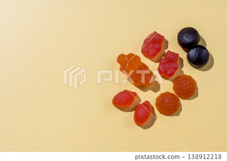 Food supplements. Vitamins jelly gummies fruit and bear shaped on yellow background, copy space Food supplements. Vitamins jelly gummies fruit and bear shaped on yellow background, copy space 138912218