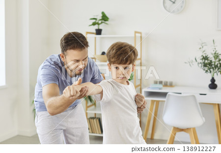 Young father teaching his preteen son martial arts, patiently demonstrating proper fighting stance. Young father teaching his preteen son martial arts, patiently demonstrating proper fighting stance. 138912227