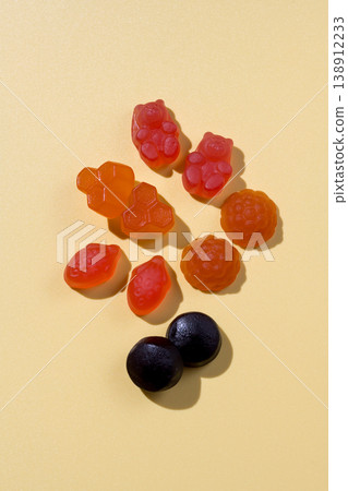 Food supplements. Vitamins jelly gummies fruit and bear shaped on yellow background Food supplements. Vitamins jelly gummies fruit and bear shaped on yellow background 138912233