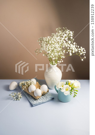 Easter eggs background. White eggs in cardboard box and gypsophila flowers in a vase. Spring holiday 138912239