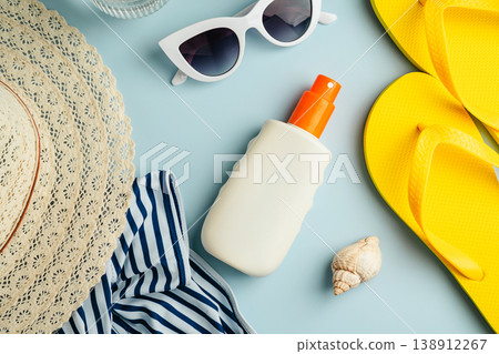 Sunscreen bottle and beach accessories. Summer travel holiday concept. Blue background flat lay. Top view Sunscreen bottle and beach accessories. Summer travel holiday concept. Blue background flat lay. Top view 138912267