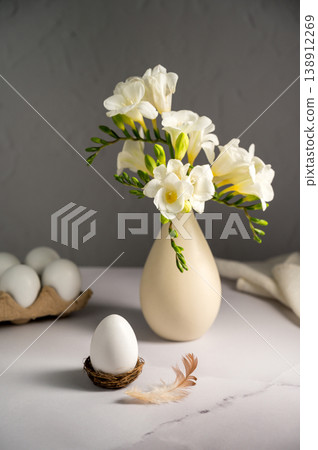 gSpring, Easter background. White freesias flowers in a vase with white eggs. gSpring, Easter background. White freesias flowers in a vase with white eggs. 138912269