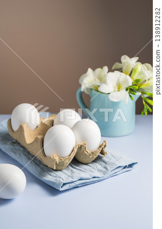Easter eggs and flowers. White eggs in cardboard box and Freesia white spring bouquet. Easter eggs and flowers. White eggs in cardboard box and Freesia white spring bouquet. 138912282