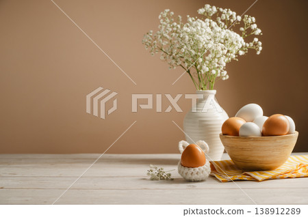Easter eggs background. White eggs in wooden bowl and gypsophila flowers in a vase. Spring holiday, copy space Easter eggs background. White eggs in wooden bowl and gypsophila flowers in a vase. Spring holiday, copy space 138912289
