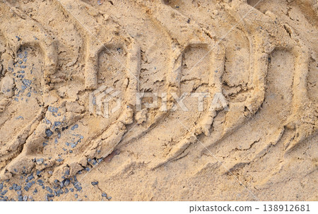 Deep tractor tire tread imprinted in dry sand. Detailed tracks from heavy equipment or industrial vehicles at a construction site, excavation concept. 138912681