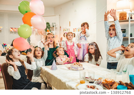 Kids celebrate birthday with balloons, cake, and games in a decorated room during afternoon party Kids celebrate birthday with balloons, cake, and games in a decorated room during afternoon party 138912768