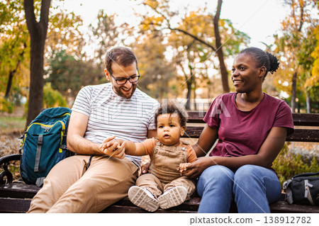 Mixed race couple is sitting on a park bench with their son Mixed race couple is sitting on a park bench with their son 138912782