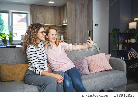 Two Women Sitting on a Couch Taking a Selfie Two Women Sitting on a Couch Taking a Selfie 138912823