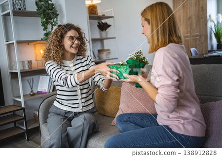 Two friends Sitting on a Couch, One Holding a Present Two friends Sitting on a Couch, One Holding a Present 138912828