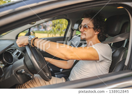 Man with curly hair driving a car and smoking a cigarette Man with curly hair driving a car and smoking a cigarette 138912845