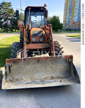 Front view of excavator loader with large bucket on city street, heavy construction equipment Front view of excavator loader with large bucket on city street, heavy construction equipment 138912890
