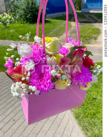 Colorful flower basket with pink handle and fresh flowers in various colors on a sunny day 138912893