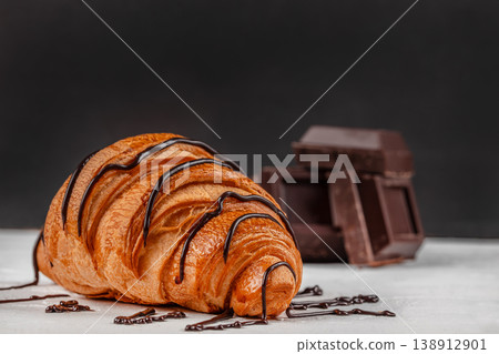 Croissant with chocolate drizzle and dark chocolate pieces. copy space 138912901