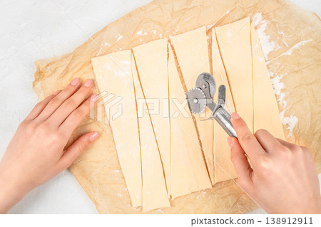 Cutting dough into triangles for croissants, top view baking process Cutting dough into triangles for croissants, top view baking process 138912911
