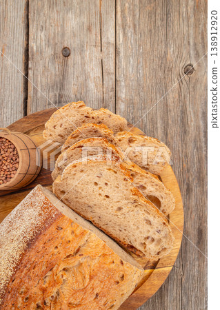 Sliced artisan bread on wooden board, rustic bakery composition with buckwheat grains 138912920