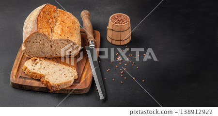 Artisan bread loaf with slices and bread knife on wooden board, rustic bakery composition Artisan bread loaf with slices and bread knife on wooden board, rustic bakery composition 138912922