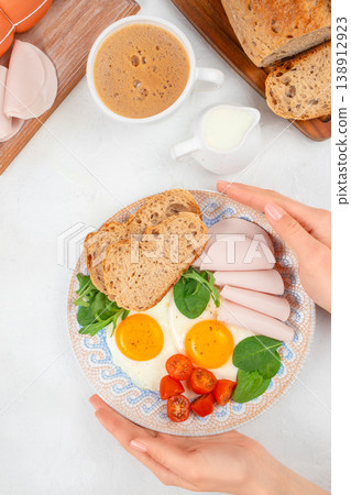 Breakfast plate with fried eggs, bread and turkey slices, top view morning meal with coffee 138912923