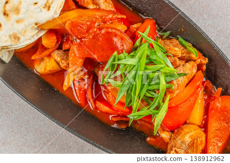 Closeup of spicy meat with bell peppers and flatbread on black plate for restaurant menu advertising Closeup of spicy meat with bell peppers and flatbread on black plate for restaurant menu advertising 138912962