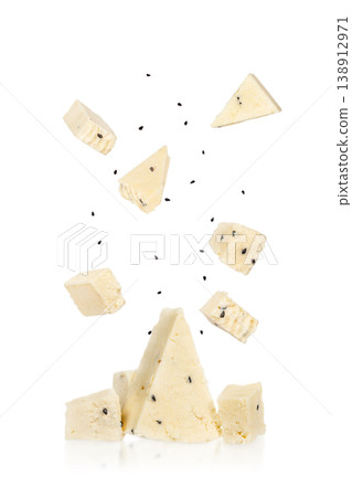 Cheese pieces falling isolated on white background, soft dairy cubes with black cumin seeds Cheese pieces falling isolated on white background, soft dairy cubes with black cumin seeds 138912971