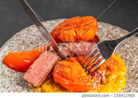 Cutting grilled pork steak with tomato and creamy sauce food action 138912988