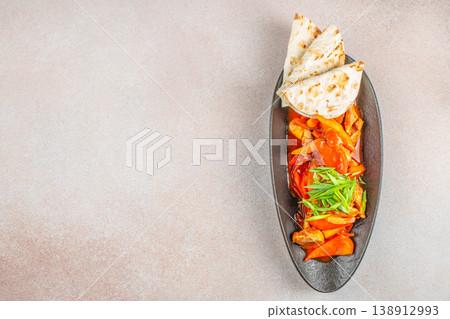 Top view of spicy meat with vegetables and flatbread on black plate with copy space for restaurant advertising Top view of spicy meat with vegetables and flatbread on black plate with copy space for restaurant advertising 138912993