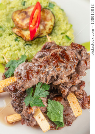 Grilled meat skewers with couscous and vegetables on light background 138913018