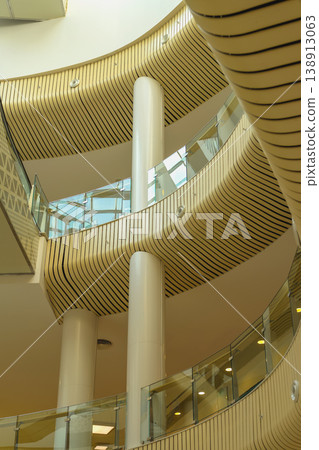 Modern interior architecture, curved balconies glass railings, columns in multi level building, wood panel texture, geometric design. Contemporary architecture, corporate space, interior design Modern interior architecture, curved balconies glass railings, columns in multi level building, wood panel texture, geometric design. Contemporary architecture, corporate space, interior design 138913063