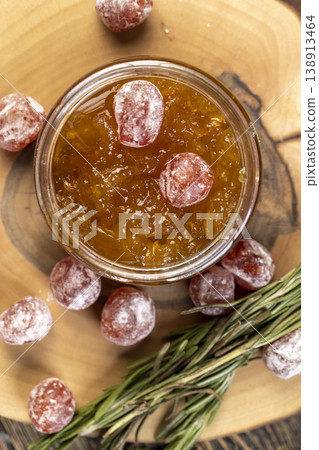 orange jam with dried kumquat fruits in sweet sugar syrup, jam for making desserts in a round glass jar on a wooden table, orange jam made from oranges and fresh citrus fruits orange jam with dried kumquat fruits in sweet sugar syrup, jam for making desserts in a round glass jar on a wooden table, orange jam made from oranges and fresh citrus fruits 138913464