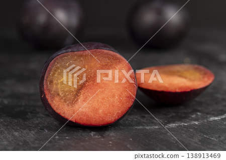cut fresh plums on the kitchen table, some beautiful pure black plums on the table, plum with red juicy sweet flesh cut into pieces cut fresh plums on the kitchen table, some beautiful pure black plums on the table, plum with red juicy sweet flesh cut into pieces 138913469