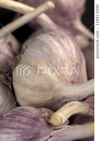 ripe purple garlic is scattered on a black table in the kitchen, garlic spices are on a black slate board in the kitchen ripe purple garlic is scattered on a black table in the kitchen, garlic spices are on a black slate board in the kitchen 138913499