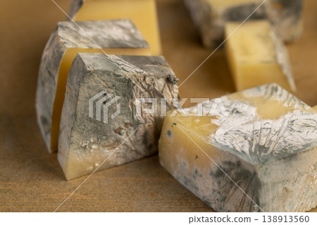 an old spoiled orange cheese with a lot of colorful mold, an inedible and dangerous cheese , the cheese is covered with mold dangerous to health an old spoiled orange cheese with a lot of colorful mold, an inedible and dangerous cheese , the cheese is covered with mold dangerous to health 138913560