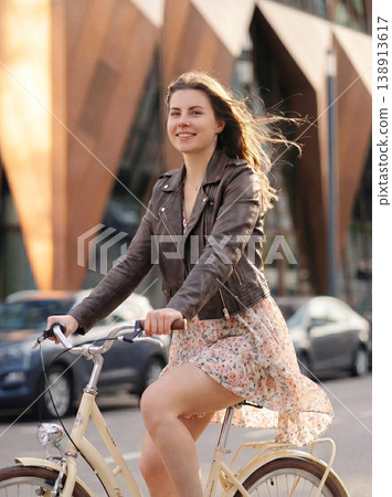 Woman smiling riding bicycle on urban street Woman smiling riding bicycle on urban street 138913617