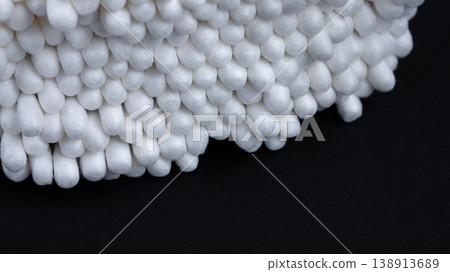 Macro close-up of a bunch of white cotton swabs on a black background with copy space 138913689
