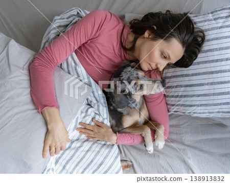 young woman sleeps with spotted dog on bed, girl and dog sleep comfortably together. 138913832
