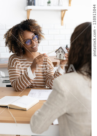 confident curly haired woman with curly dark hair, designer or realtor, shows mock up house.  138913844