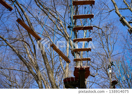 Wooden rope course obstacles and platforms installed between trees in adventure park 138914075