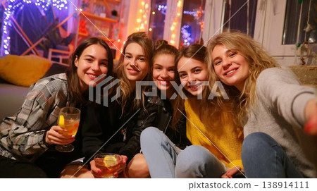 Friends gen-z gather in a cozy living room with drinks and lights for a fun night together 138914111