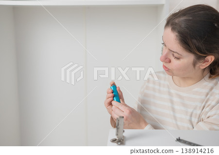 A Caucasian woman assembles a wardrobe. She understands the hardware. A Caucasian woman assembles a wardrobe. She understands the hardware. 138914216