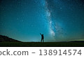 夜晚，一位年輕人指著草地上明亮的銀河。 138914574