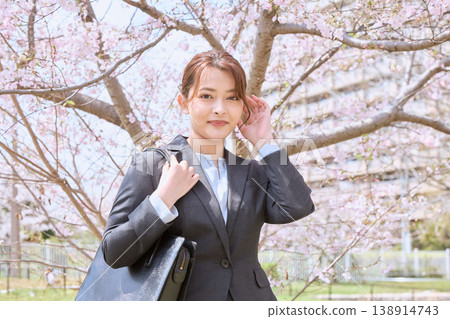 一位身著職業套裝的年輕女子在櫻花樹下擺姿勢；展現了春天新生活的景象；一位女大學生正在找工作。 138914743