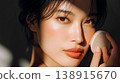 A close-up of a woman's face as she applies foundation to her cheeks in the morning sunlight. 138915670