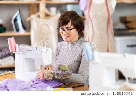 Woman tailor sews clothes in sewing machine Woman tailor sews clothes in sewing machine 138915741